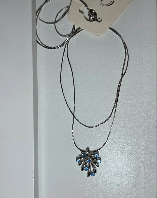 Silver-colored pendant with blue stones on a chain.