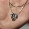 Silver-colored pendant with blue stones on a chain.