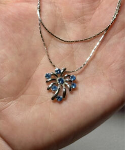 Silver-colored pendant with blue stones on a chain.