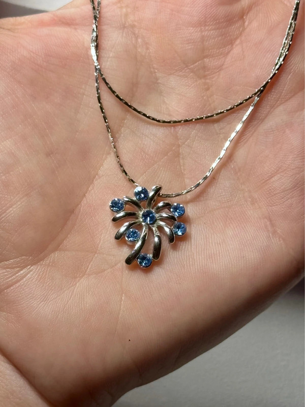 Silver-colored pendant with blue stones on a chain.