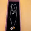 Silver-tone necklace with a pendant set with a yellow stone and an A initial.