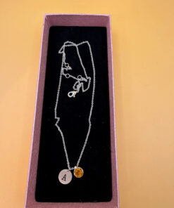 Silver-tone necklace with a pendant set with a yellow stone and an A initial.
