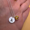 Silver-tone necklace with a pendant set with a yellow stone and an A initial.