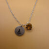 Silver-tone necklace with a pendant set with a yellow stone and an A initial.