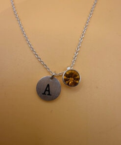 Silver-tone necklace with a pendant set with a yellow stone and an A initial