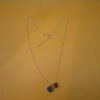 Silver-tone necklace with a pendant set with a yellow stone and an A initial.