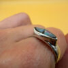 A silver ring featuring a natural opal, size Q
